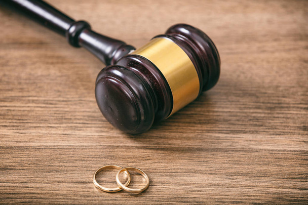 Divorce concept. Wedding rings and judge gavel on wooden background, copy space - Photo, Image
