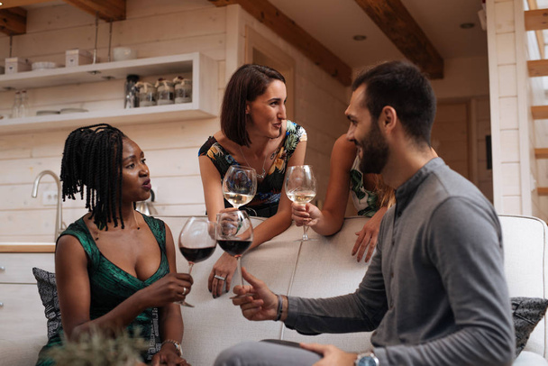 Mutlu genç arkadaş grubu evde şarap içer.  - Fotoğraf, Görsel