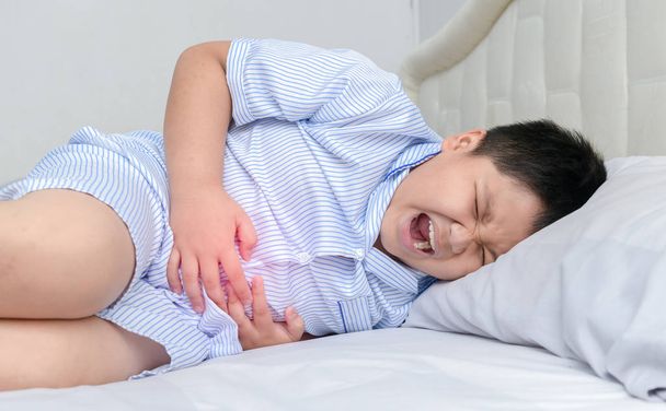Aasialainen lihava lapsi kärsii vatsakivusta ja punaisesta pisteestä, joka osoittaa kivun sijainnin. terve käsite
 - Valokuva, kuva