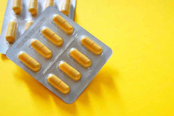 Two packs of yellow capsule tablets on a yellow background - Foto, Bild