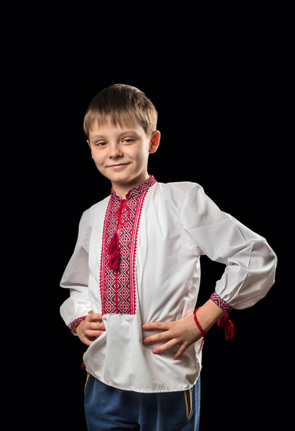 Menino bonito em uma camisa ucraniana tradicional branca em um fundo preto
 - Foto, Imagem