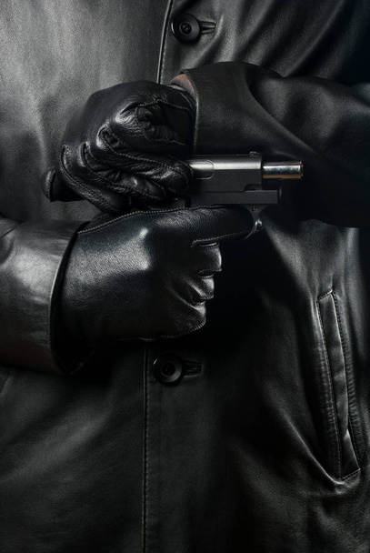 Bandido en ropa negra y guantes recarga el arma
 - Foto, imagen