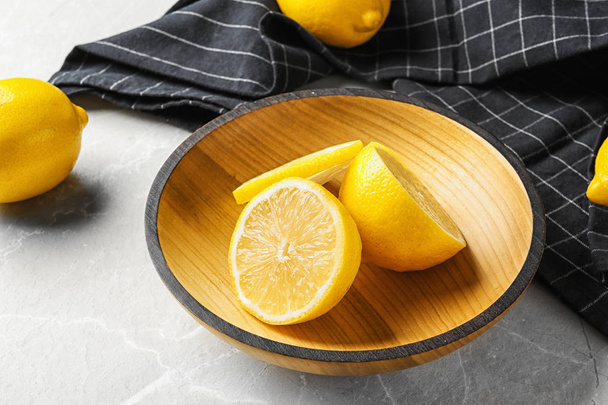 Bowl with lemons and fabric on light background - Zdjęcie, obraz