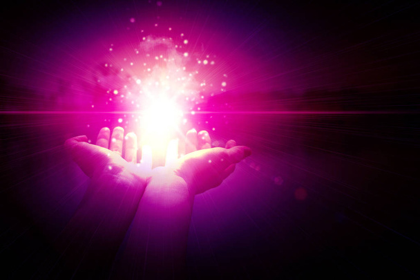 Partículas mágicas nas palmas das mãos de uma mulher num fundo escuro e roxo. Partículas mágicas, um clarão de luz, o fluxo de energia
 - Foto, Imagem