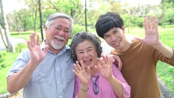 公園で父と母と息子。引退した中国の父と母は、彼の息子はお互いを抱き、幸せで微笑んでいます。成功した家族愛と関係の概念. - 映像、動画