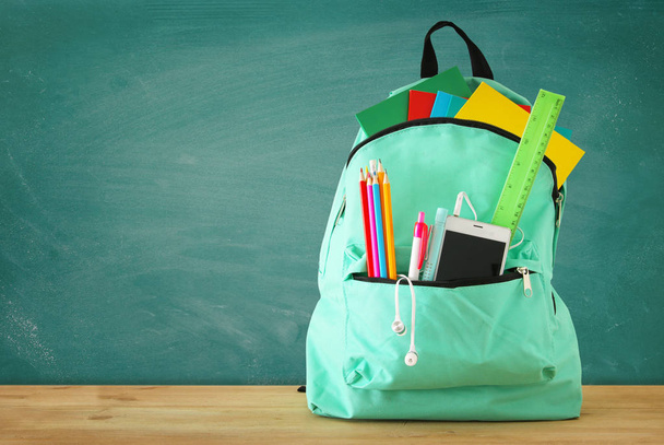 school bag with stationery and notebooks in front of blackboard. Back to school concept - 写真・画像