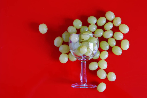 Fresh green grapes is scattered in the kitchen near a glass - Photo, Image