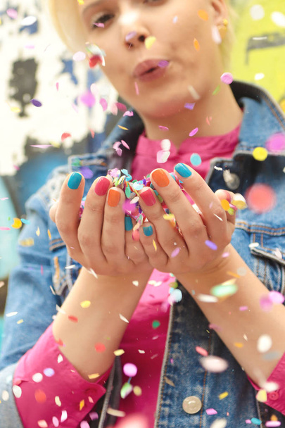 Fashionable girl with bright colorful nail designs blows confetti in her hands.Nails art.Color manicure. - Foto, afbeelding