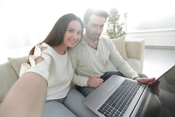 married couple with laptop sitting on the couch - Photo, Image