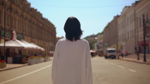 brunette nainen kävelee yllään valkoinen villapaita ja musta hame
 - Materiaali, video