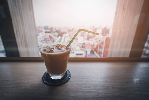 Ledové kávy sklenici na dřevěný stůl v kavárně s pozadí rozmazané města - starý filtr - Fotografie, Obrázek