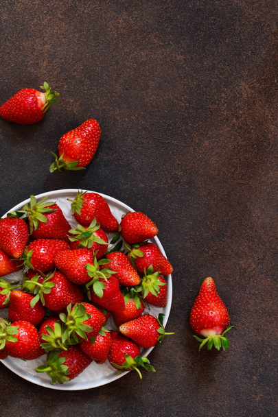Fresh, juicy strawberries in a plate on a dark rustic background. Proper nutrition. Organic food. - Фото, изображение