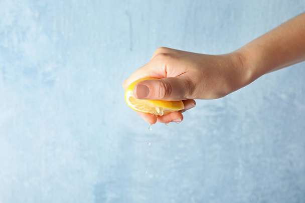 Young woman squeezing lemon on color background - Fotografie, Obrázek