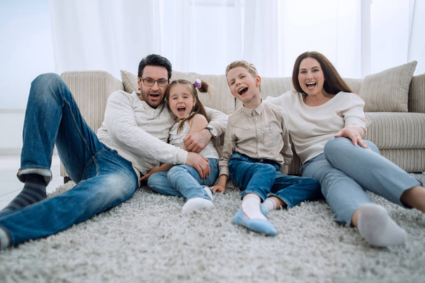 happy family sitting on the carpet in the living room. - Φωτογραφία, εικόνα