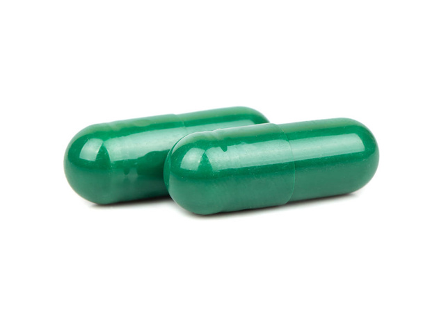 Twee groene kruiden capsule geïsoleerd op witte achtergrond - Foto, afbeelding