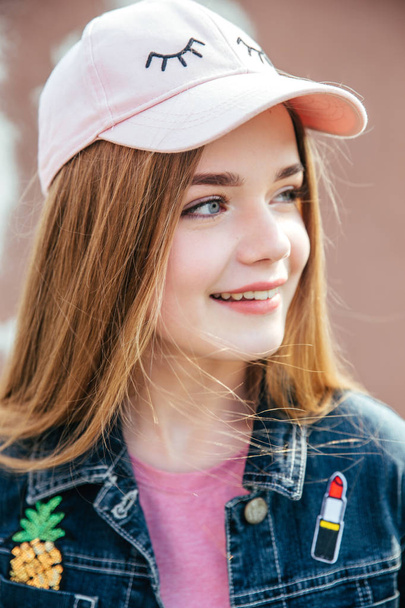 Portrait closeup beautiful young girl in city. Smiling girl in hat - Valokuva, kuva