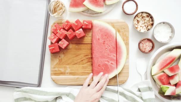 Snijden van watermeloen in kubussen voor het voorbereiden van watermeloen voorgerechten gedoopt in chocolade en sprinked met zeezout en amandelen - Video