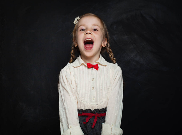 Happy Child Girl Laughing on Blackboard Background. Kid Creativity and Education Concept - Fotoğraf, Görsel