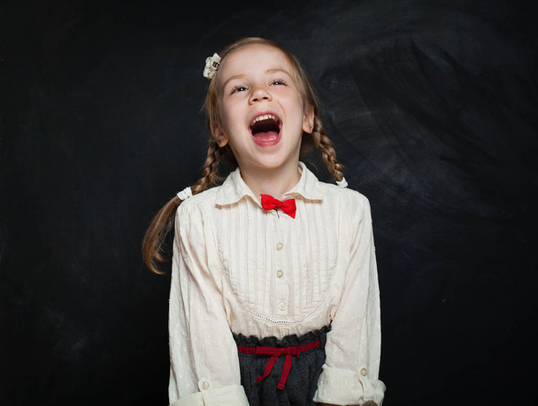 Happy surprised child having fun and laughing on chalk board background. Back to school sale concept - Foto, immagini