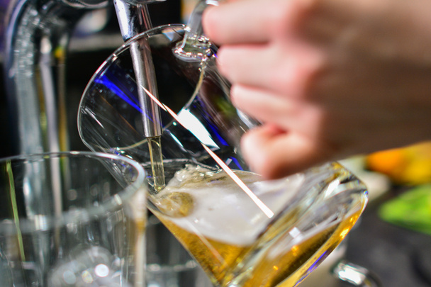 Primer plano de la mano del barman en el grifo de la cerveza vertiendo una cerveza de cerveza de barril de barril
 - Foto, imagen