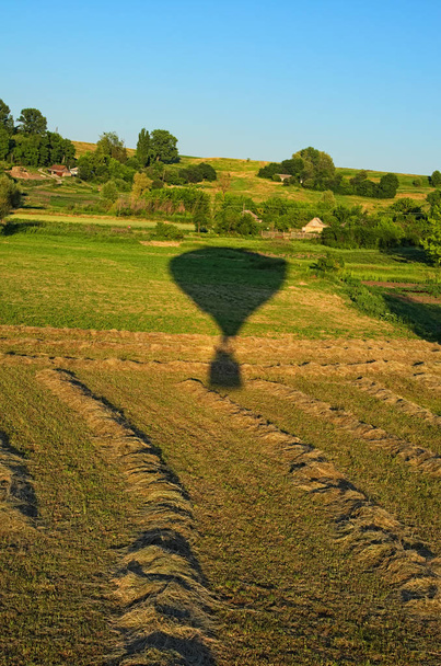 Εναέρια θέα πάνω από το πεδίο σε μια ηλιόλουστη καλοκαιρινή μέρα. Αερόστατο ζεστού αέρα απογειώθηκε από το πεδίο στο χωριό. Η σκιά αέρα μπαλόνι στο πράσινο χορτάρι. Περιοχή Κίεβο, Ουκρανία. - Φωτογραφία, εικόνα