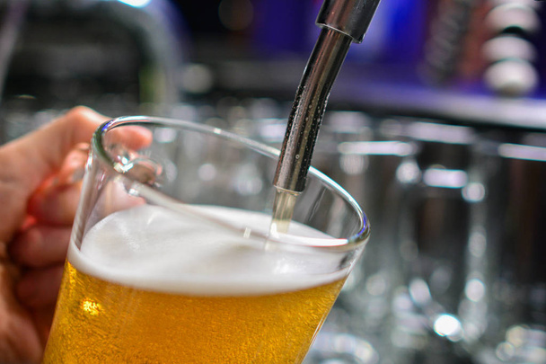 生ビールを注ぐビールのタップでバーマンの手のクローズアップ - 写真・画像