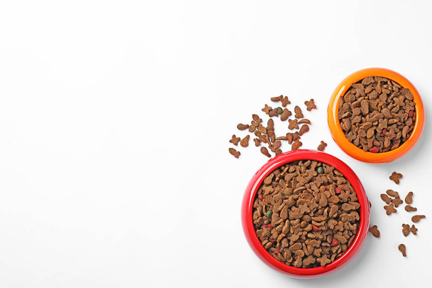 Bowls of dry pet food on white background, top view - Fotoğraf, Görsel