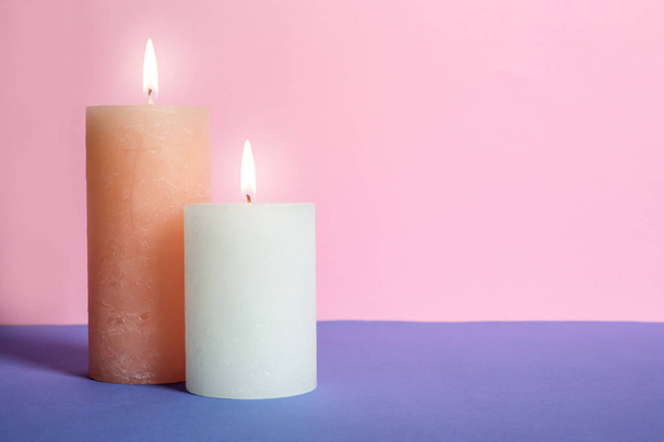 Decorative wax candles on table against color background - Fotoğraf, Görsel