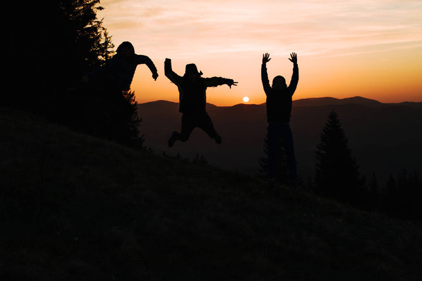 Silhouette drei Menschen springen gemeinsam bei Sonnenuntergang auf - Foto, Bild