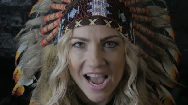 close up portrait of red indian woman hunter with feathers on her head screams - Footage, Video