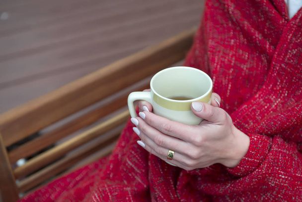 Female holding cup of hot drink in cozy atmosphere - Photo, Image