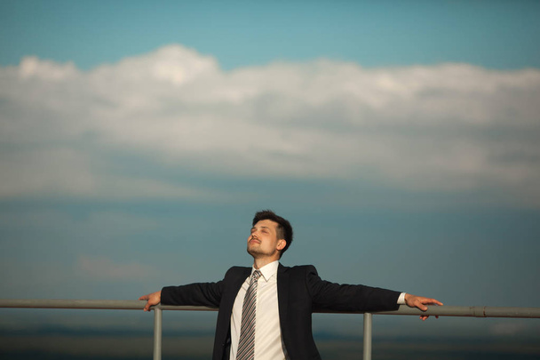 handsome young man in a suit resting with closed eyes against a sky in summer - Foto, Imagem