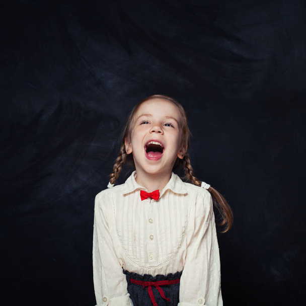 少女は叫んで、楽しい時を過します。コピー スペース空の黒板背景が付いて幸せな子。学校販売コンセプトに戻る - 写真・画像