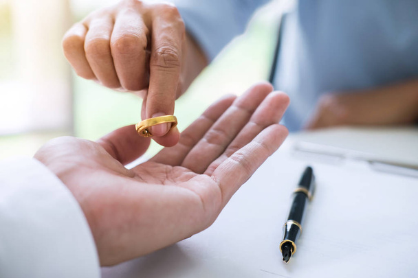 Husband and wife are signing decree of divorce (dissolution or cancellation) of marriage filing divorce papers and returning wedding ring. - Foto, Bild