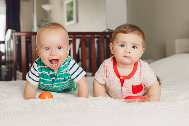 Group portrait of two white Caucasian cute adorable funny baby boys sitting together on bed sharing toy.Friendship childhood concept. Best friends forever. Early years development - Photo, Image