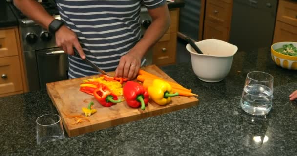 Man cutting vegetables in the kitchen at home 4k - Felvétel, videó