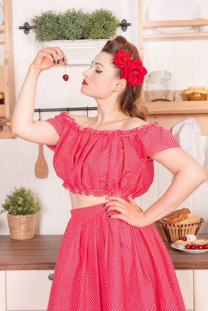 自宅キッチンでの水玉ドレスを赤いピンでポーズをとる彼女の髪に花を持つ美しい少女 - 写真・画像