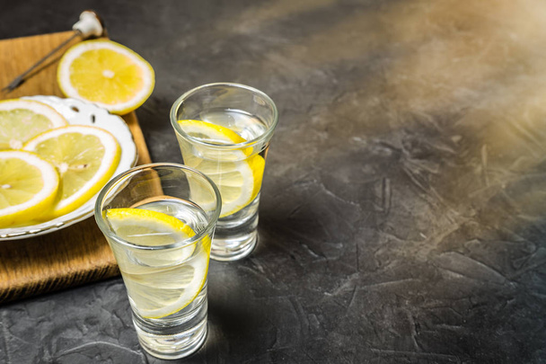 Glass of vodka. And lemon slicing on a plate. Place for your text. - Foto, imagen