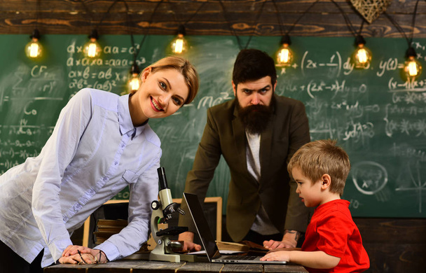 Tutor asks the tutee to find the definition in the textbook, Happy teacher in classroom, Home tutor helping boy with studies using modern laptop, - Фото, зображення