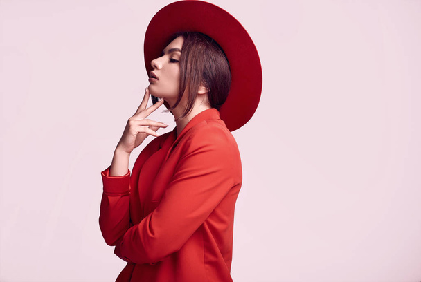 Retrato de mulher bonita elegante em um terno elegante vermelho e chapéu largo isolado no fundo branco no estúdio
 - Foto, Imagem