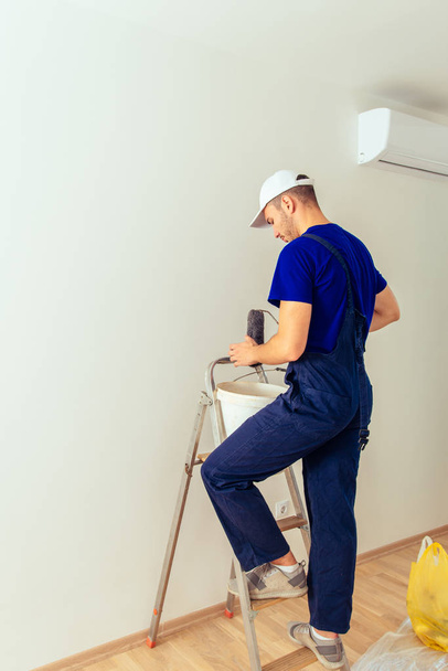 Painter man renovate apartment and coloring wall with paint roller - Foto, Bild