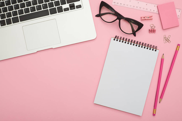 schönes Flatlay mit Laptop, Brille und Schreibwaren auf rosa de - Foto, Bild