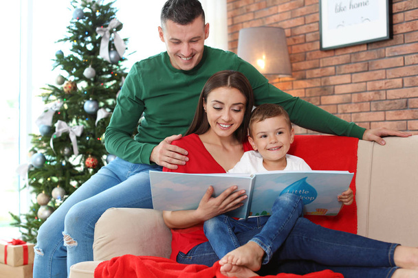Happy parents and child reading fairy tales together at home on Christmas day - Foto, imagen
