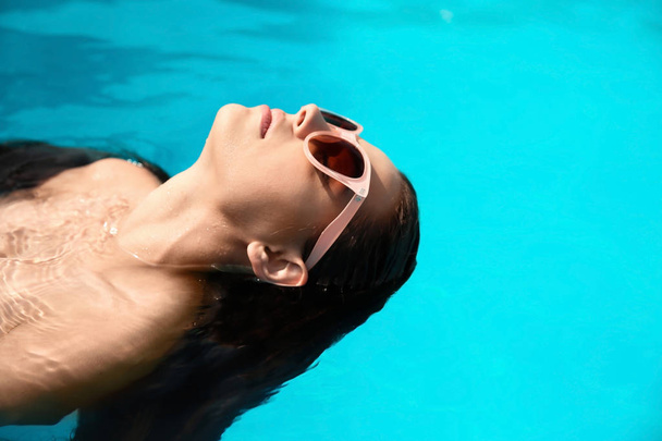 Όμορφη νεαρή γυναίκα με το κολύμπι στην πισίνα μπλε - Φωτογραφία, εικόνα