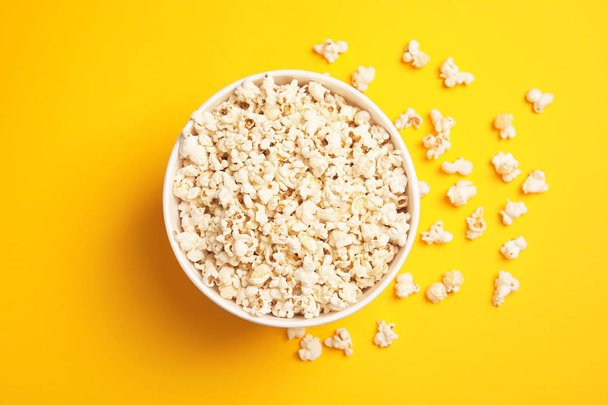 Paper bucket with tasty fresh popcorn on color background, top view - Fotoğraf, Görsel