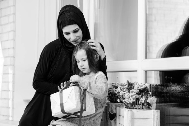 Středního východu matka a dívka s dárkovou krabičku. Muslimské rodiny způsobu života. Spokojený úsměv arabské parrent a dítě. Černá a bílá. - Fotografie, Obrázek
