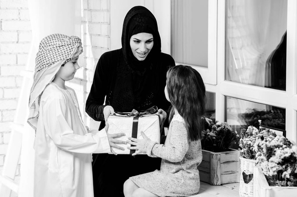 Αραβικά μητέρα δίνει δώρο για το αγόρι και το κορίτσι. Μουσουλμανική οικογένεια. BW - Φωτογραφία, εικόνα