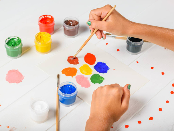 The girl draws a colorful flower on a white wooden table. Creative kit. Hobby and style. - Photo, Image