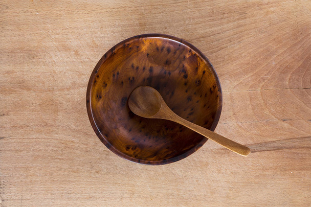 Wooden bowl and spoon on a wooden background from above. Studio shot. Kitchen utensil. - Valokuva, kuva