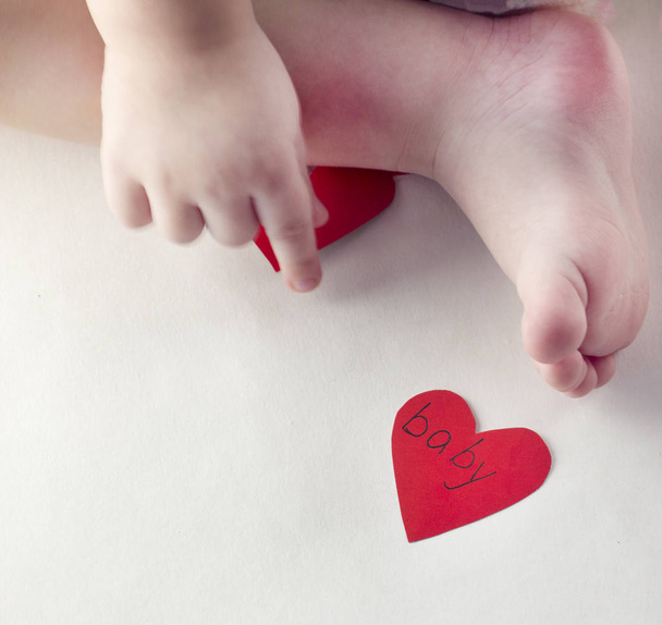 Handle and a baby's leg and a red heart - Foto, Imagen